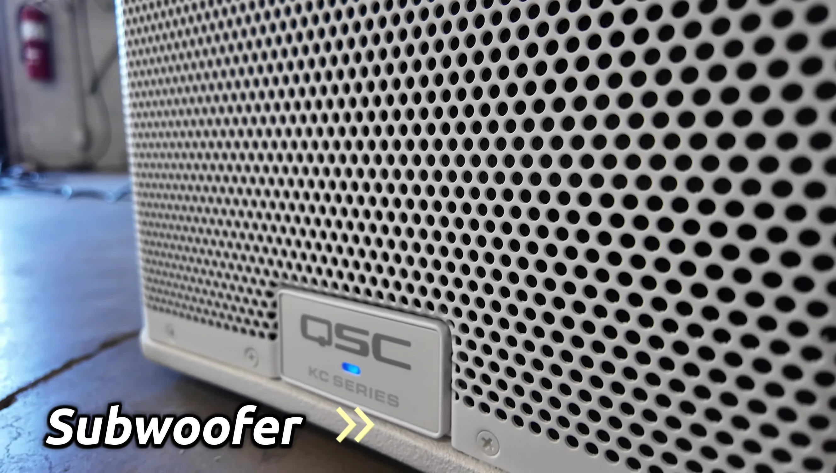 Close-up of the QSC KC12 subwoofer, highlighting the bass level adjustment.