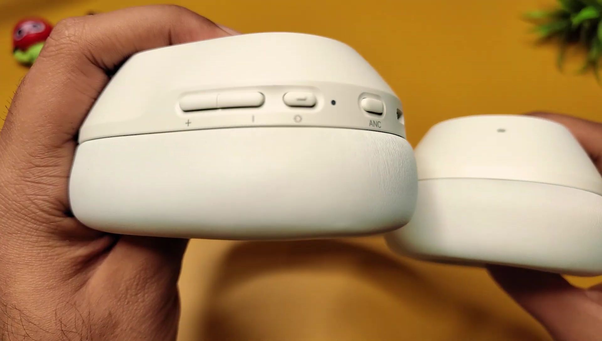 Close-up of the Noise Airwave Max 5 earcup controls, showing buttons for volume, play/pause, and noise cancellation.