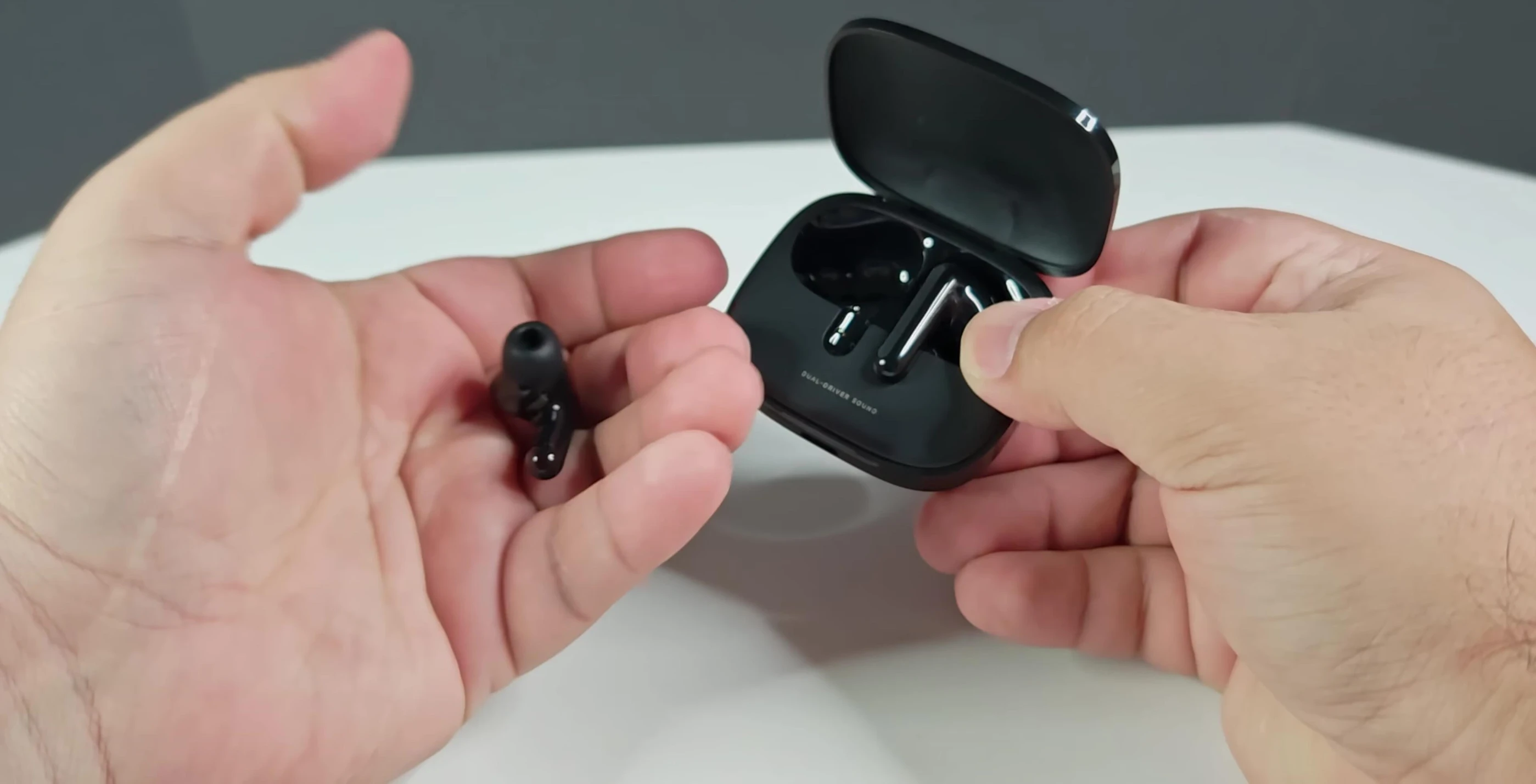 Image of the earbuds, highlighting their glossy design and touch controls.