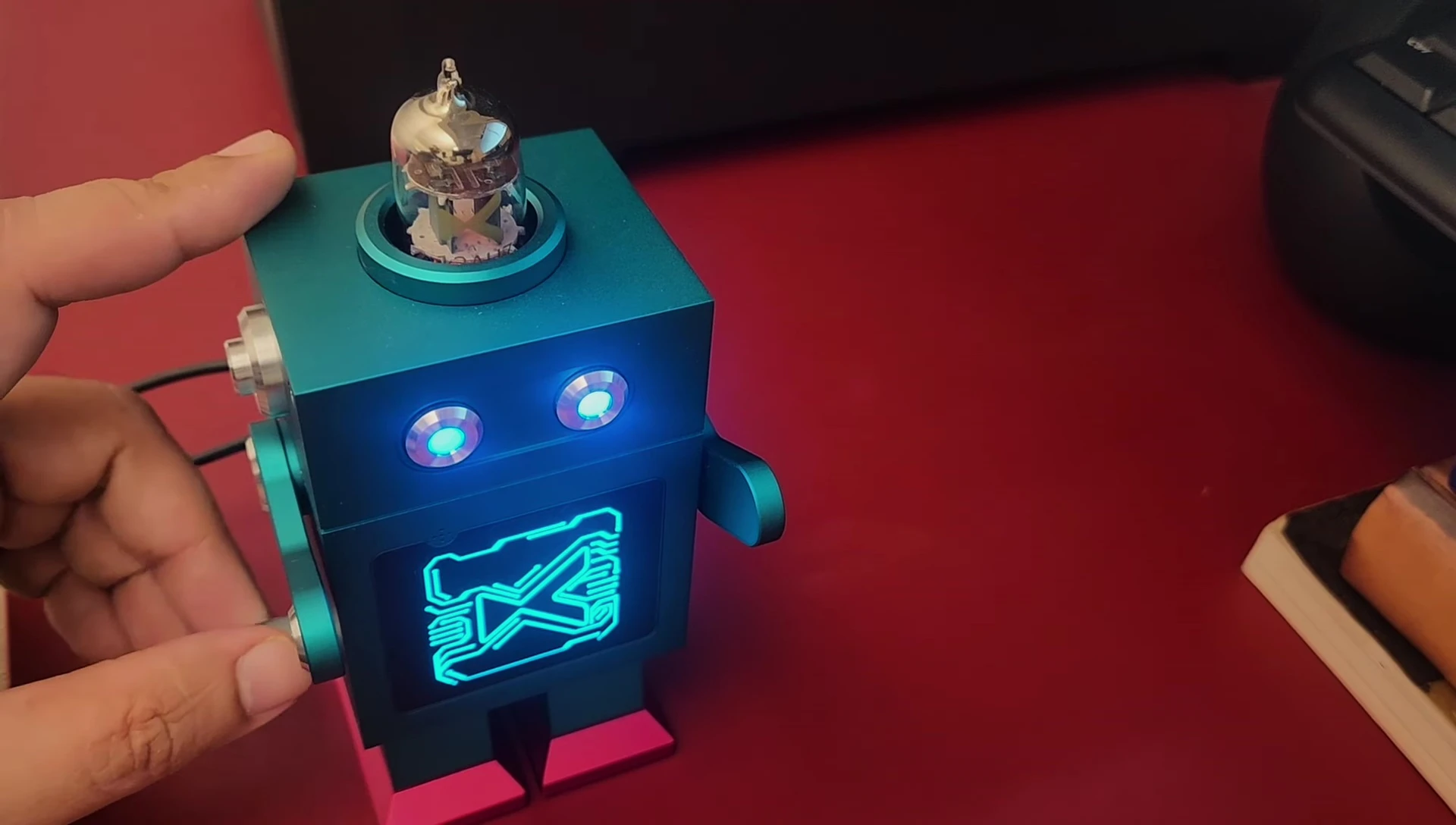 The reviewer demonstrates the volume controls using the robot's arms.