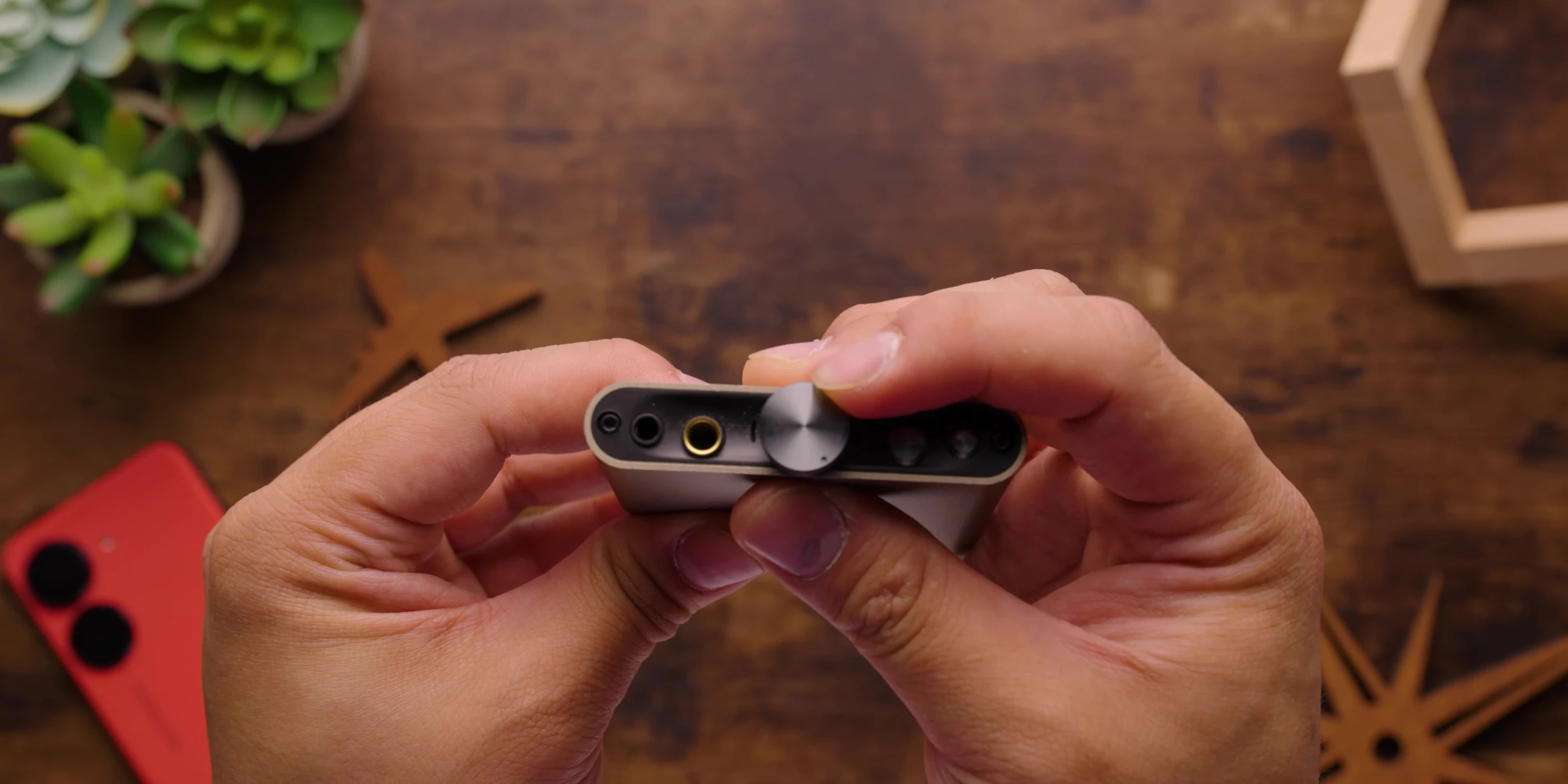 Hand holding the iFi Hip-DAC 3, showcasing the size and weighted knob.