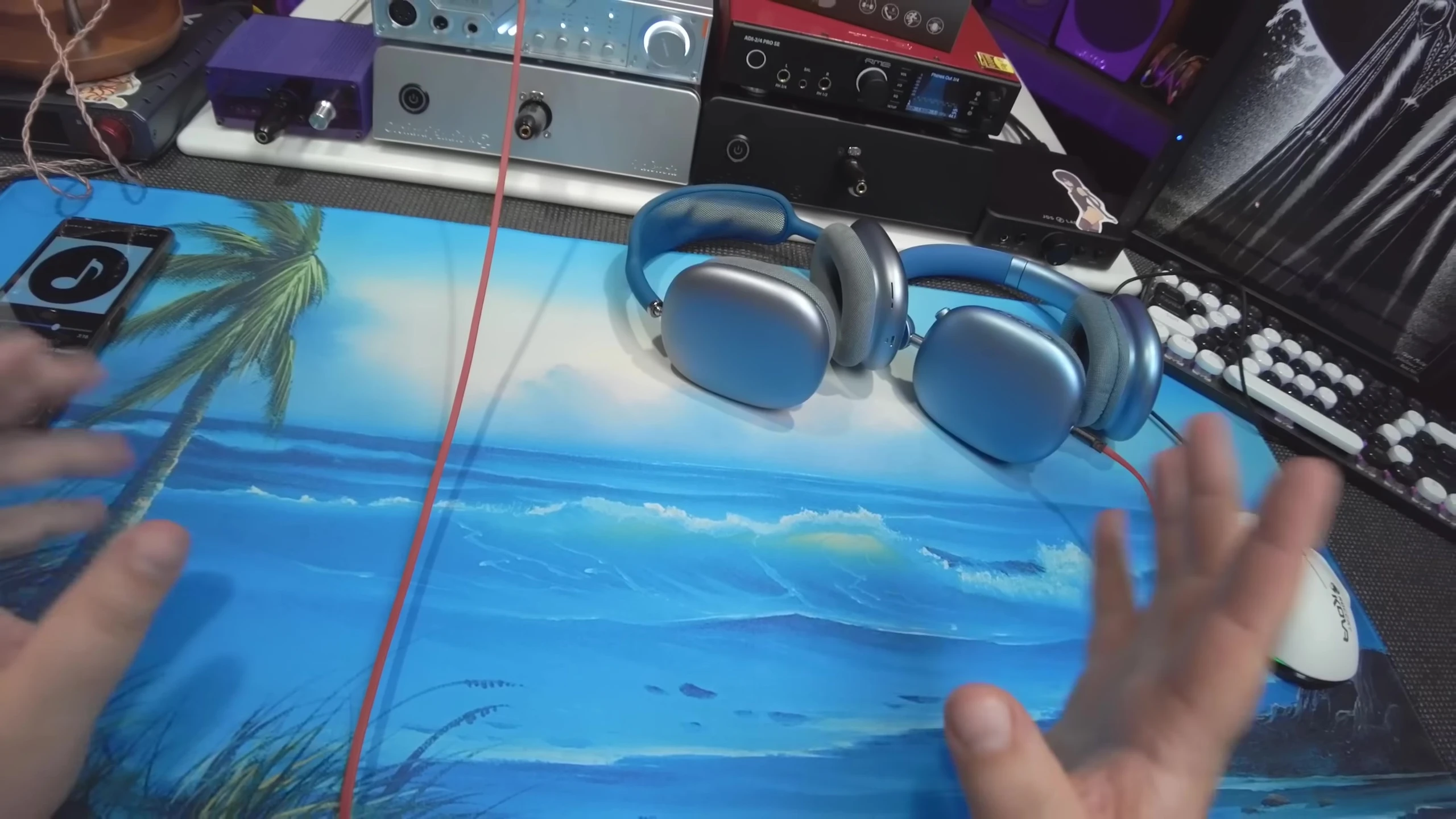 Screenshot displaying the presenter holding two inexpensive Bluetooth headphone knockoffs.